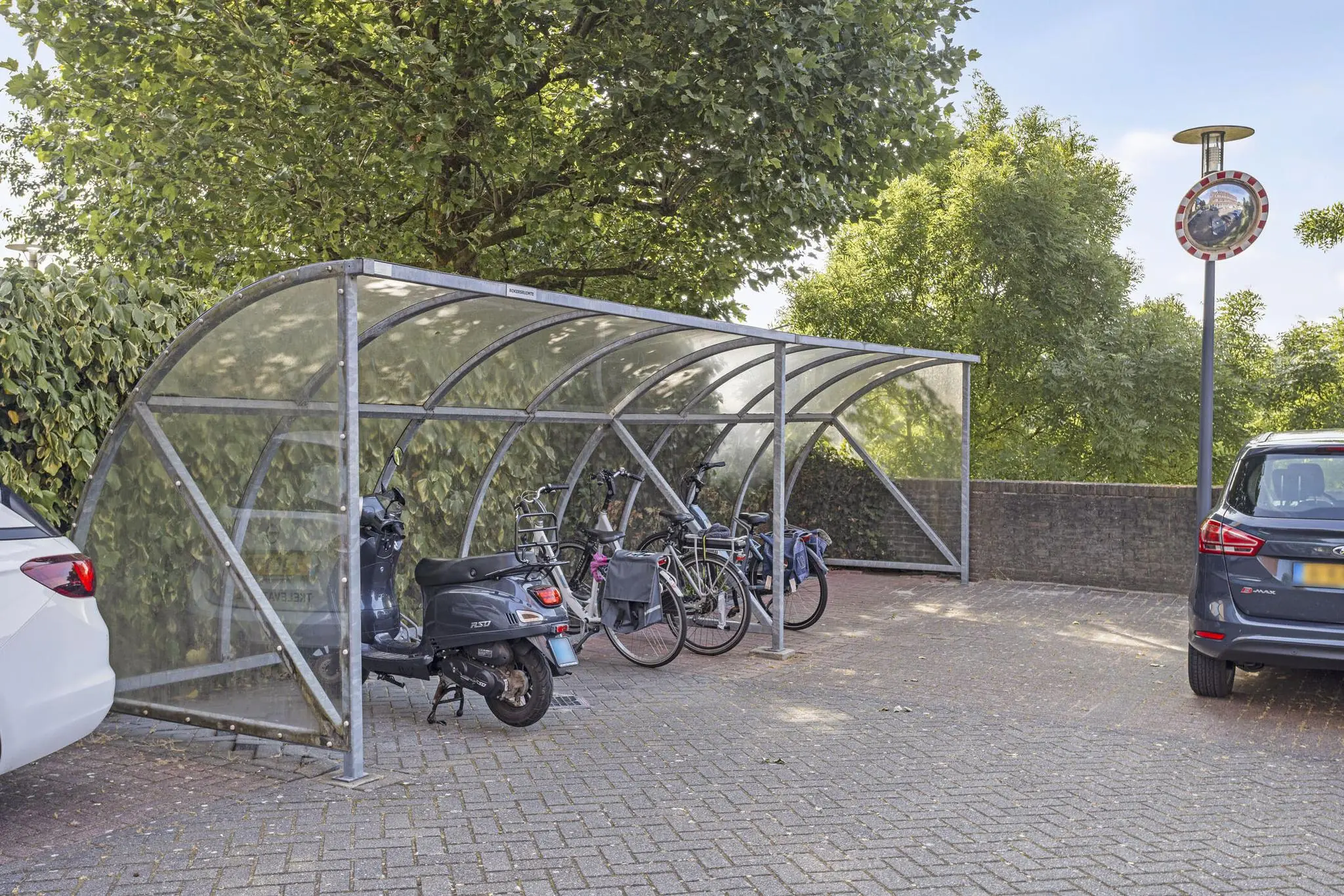Overdekte fietsenstalling met meerdere fietsen en een scooter aan de Fascinatio Boulevard.